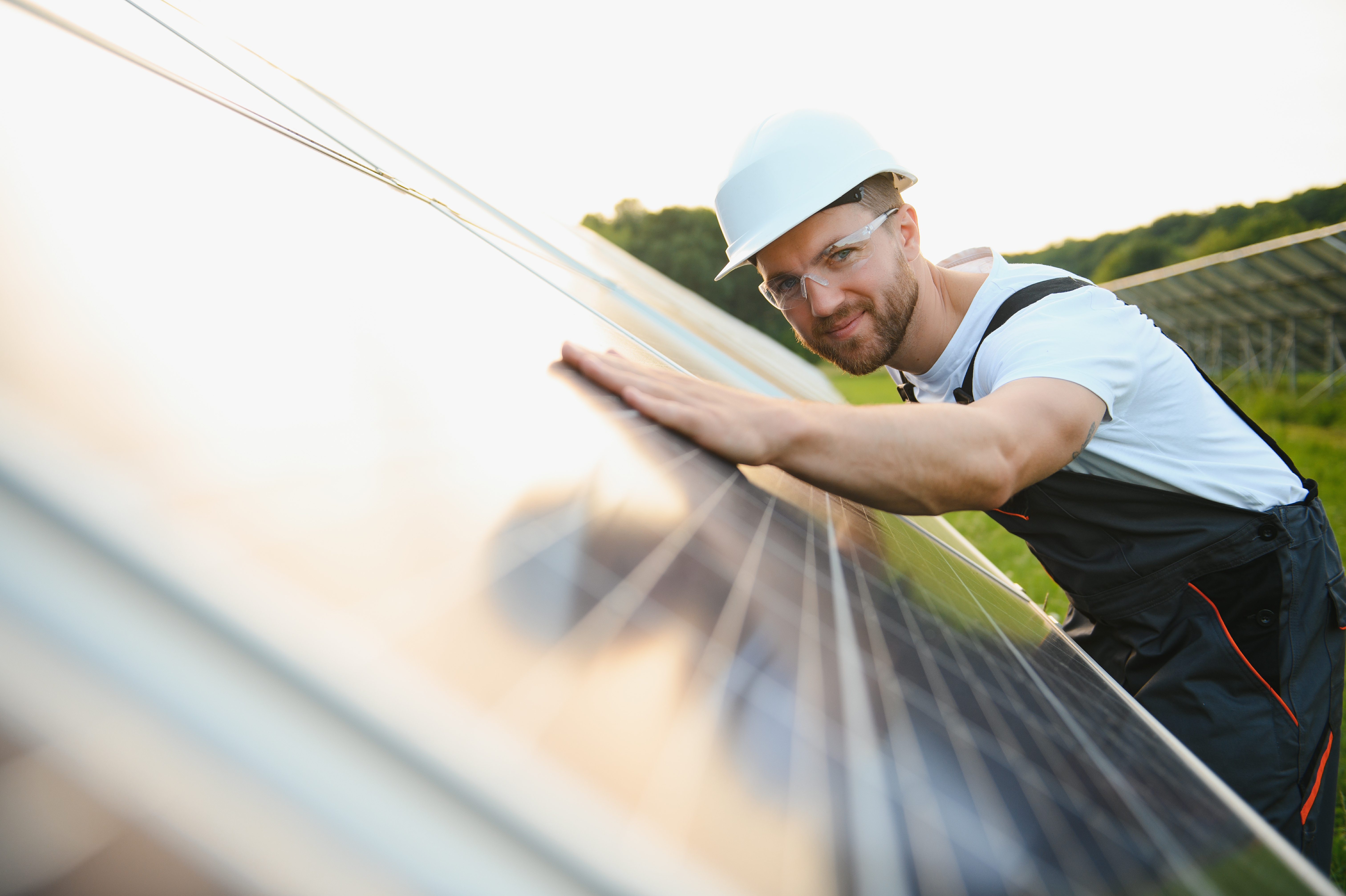 Man engineer in uniform working on solar panels power farm. Solar panel field. Clean energy production. Green energy
